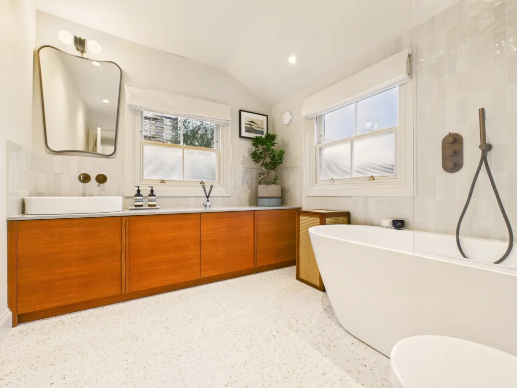 Family bathroom with a freestanding bath, long oak vanity, white handmade tiles, terrazzo floor and bronze fittings