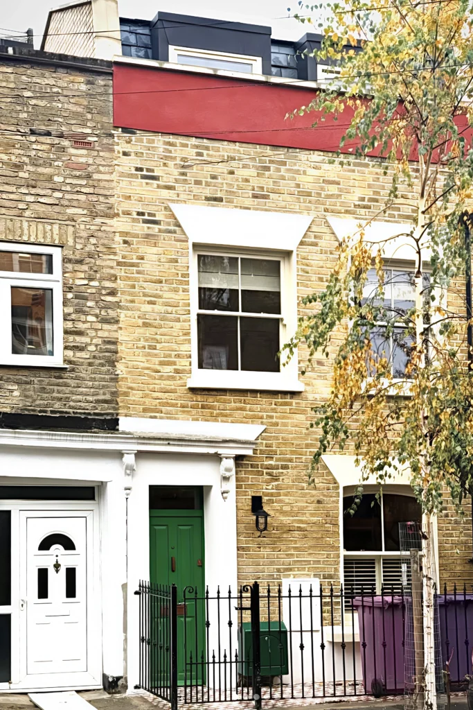 Front elevation of the Victorian terraced house in Bow with yellow stock brick, white sash windows, a green front door and a slate mansard loft
