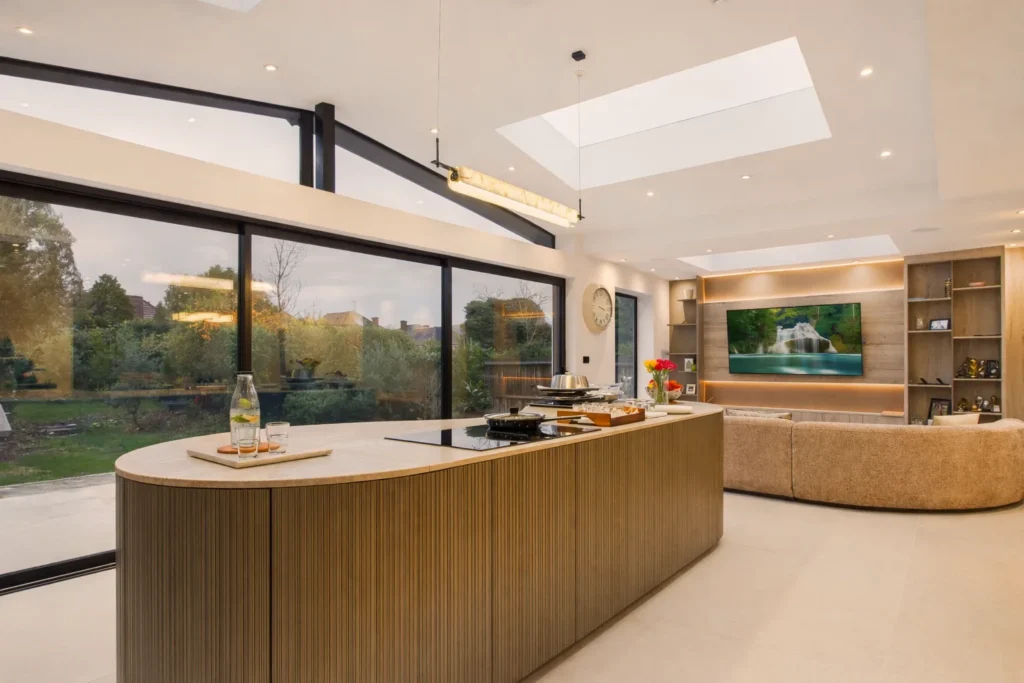 Kitchen island looking across the open-plan space to the living area, media wall and sliding doors to the garden