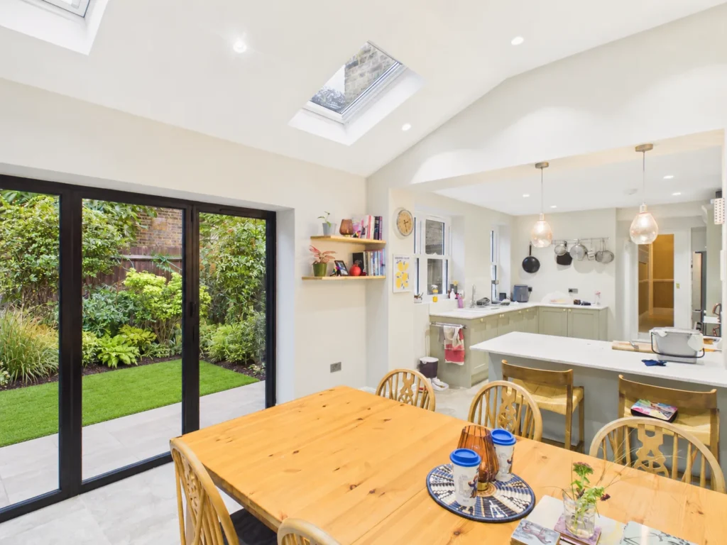 Vaulted ceiling with Velux rooflights over the dining table, with rear bifold doors to the garden and the kitchen beyond