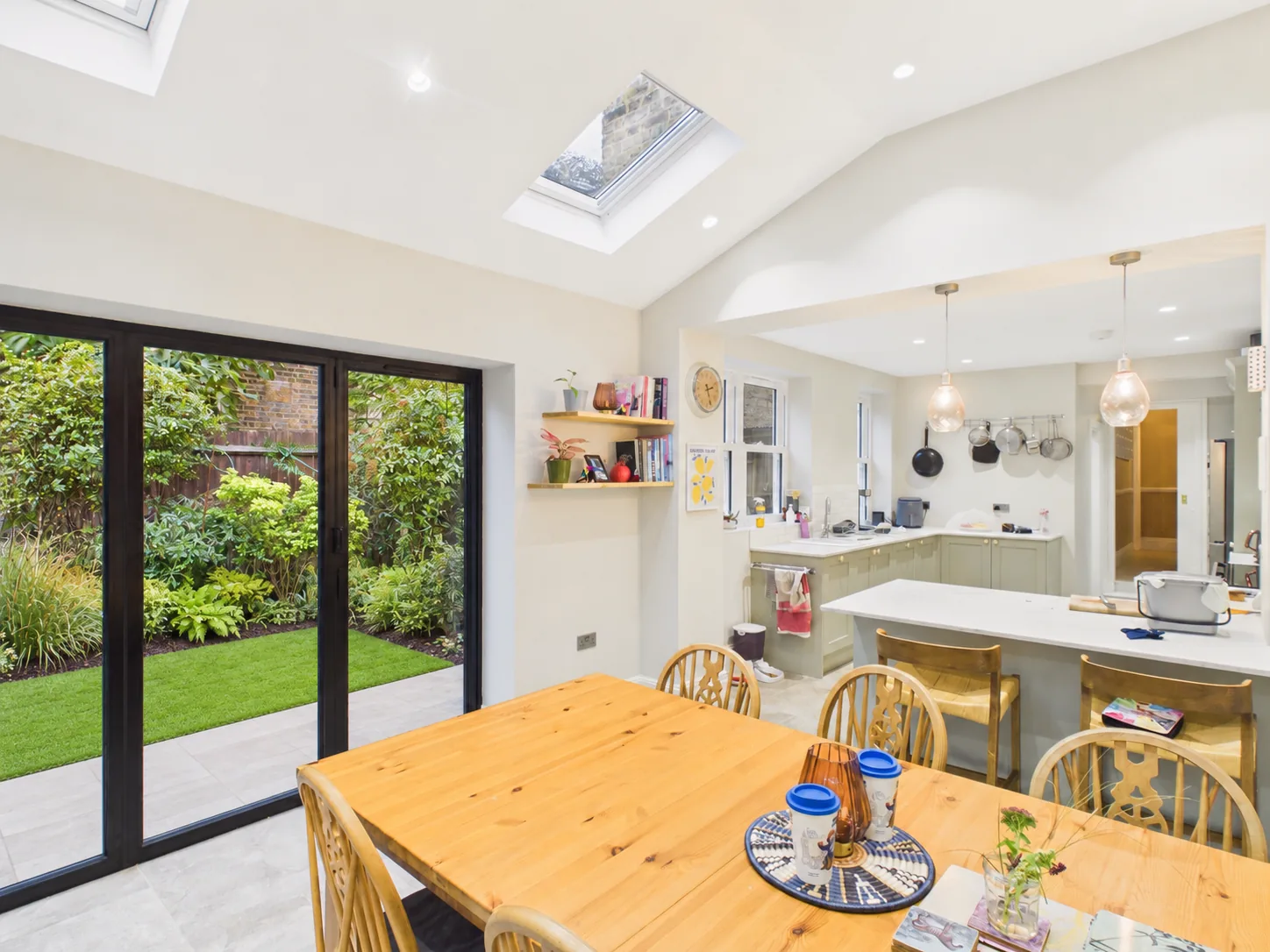 Vaulted ceiling with Velux rooflights over the dining table, with rear bifold doors to the garden and the kitchen beyond